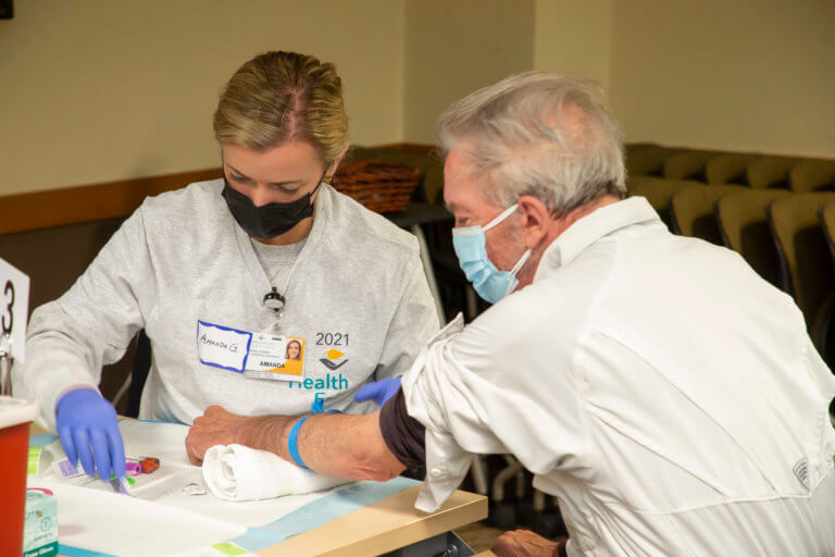 Nurse administering a blood test to a middle-aged man