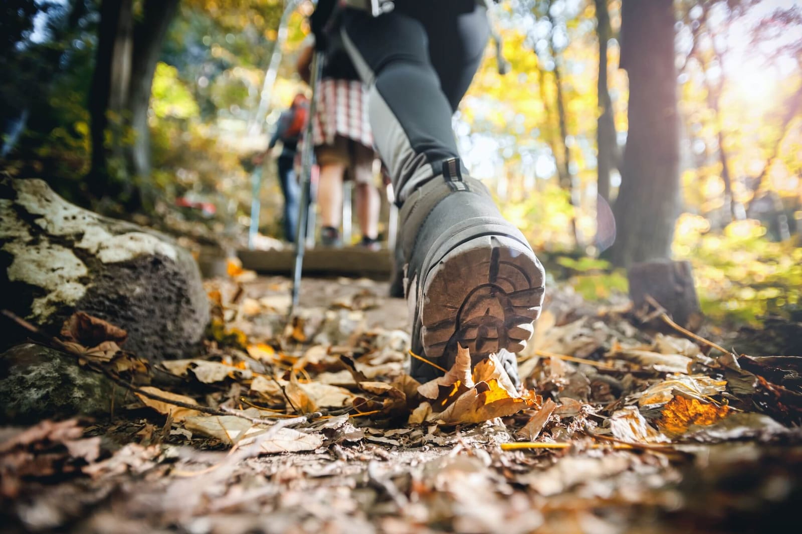 Hiker woman with trekking sticks climbs steep on mountain trail, focus on boot how to train for backpacking