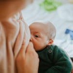 Mother breastfeeding baby at home