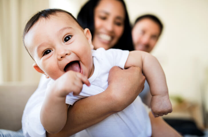affectionate couple hugging baby at home