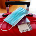Boarding pass, passport, and face mask on red table
