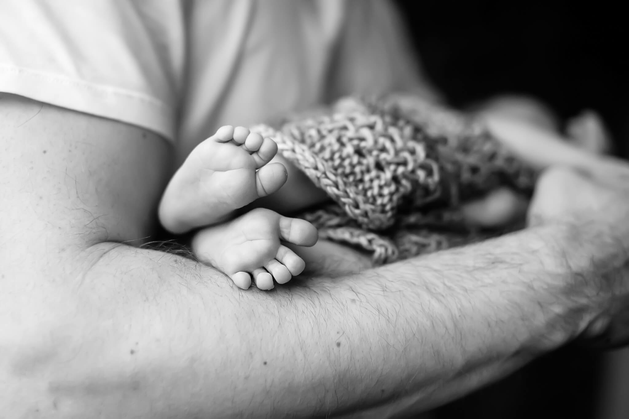 greyscale baby feet in father's hands