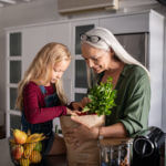 Grandma and granddaughter holding bag of groceries