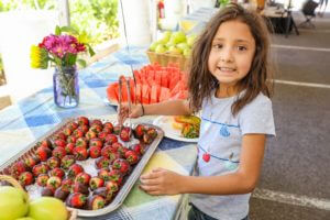 young girl picking out chocolate covered strawberries