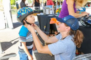 woman helping small boy buckle helmet