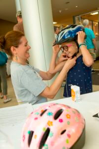 woman assisting child buckle helmet