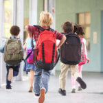 Group of elementary school kids running at school, back view