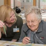 staff member doing craft with elderly woman on oxygen