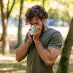 managing allergy season in colorado a man with brown curly hair blows his nose outside
