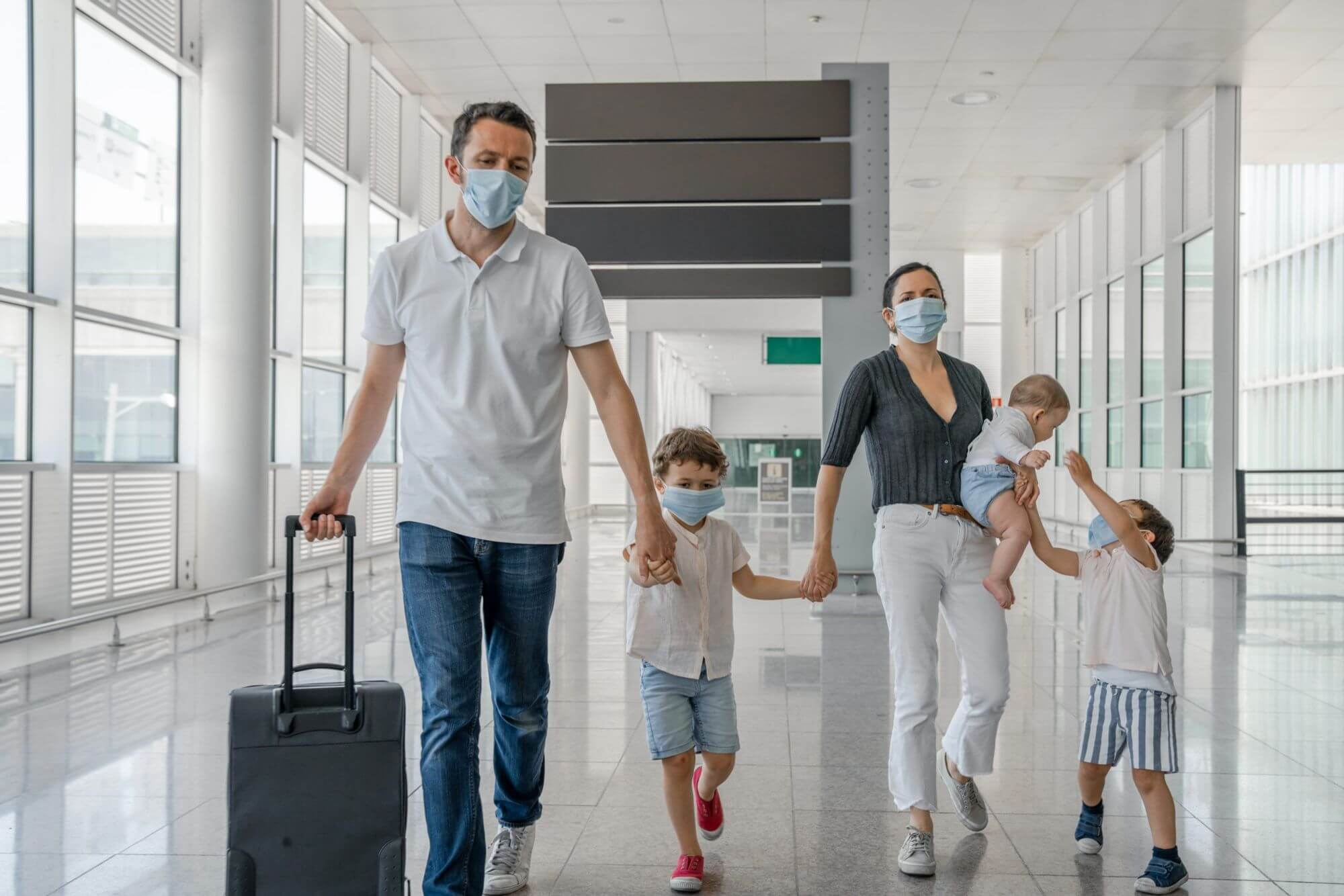Masked family with suitcase walking through airport