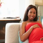 Happy pregnant woman posing on couch