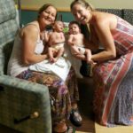 two women holding newborns next to each other