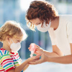 Woman putting hand sanitizer in young child's hands