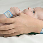 Baby holding mother's thumb in hospital