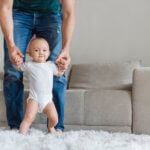 father holding up baby in living room