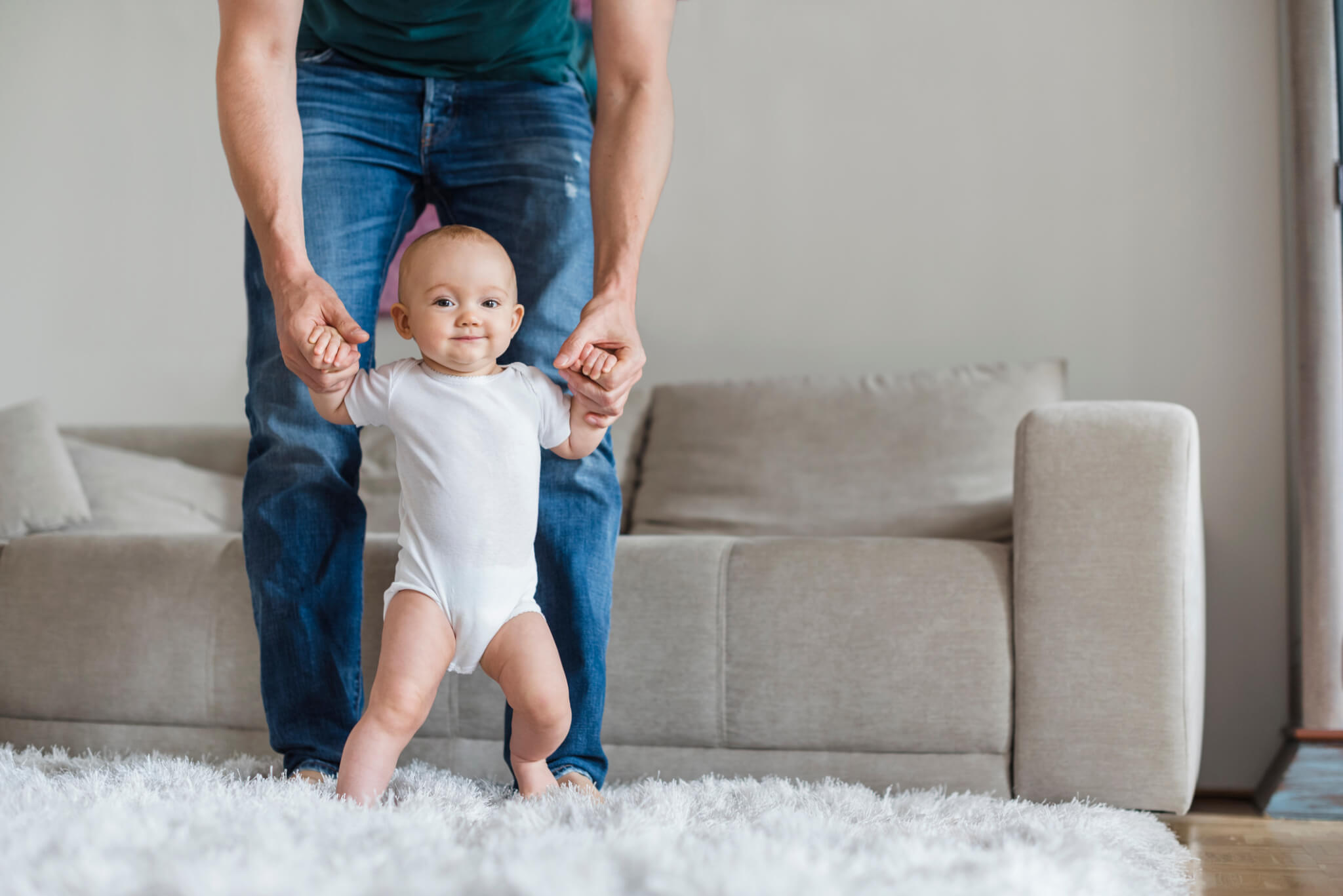 father holding up baby in living room