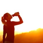silhouette of woman hydrating after workout in sunset