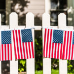 hanging american flags on white picket fence