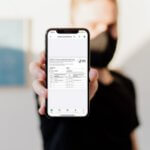 man holding out phone with myVaccine app