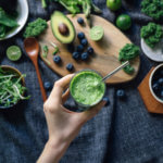 Flat lay of fresh and healthy green fruits and vegetables on a rustic wooden board