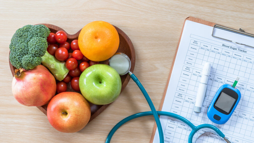 heart shaped bowl of fruit with stethoscope and chart