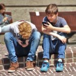 Teens sittiing in the park on there phones too much screen time