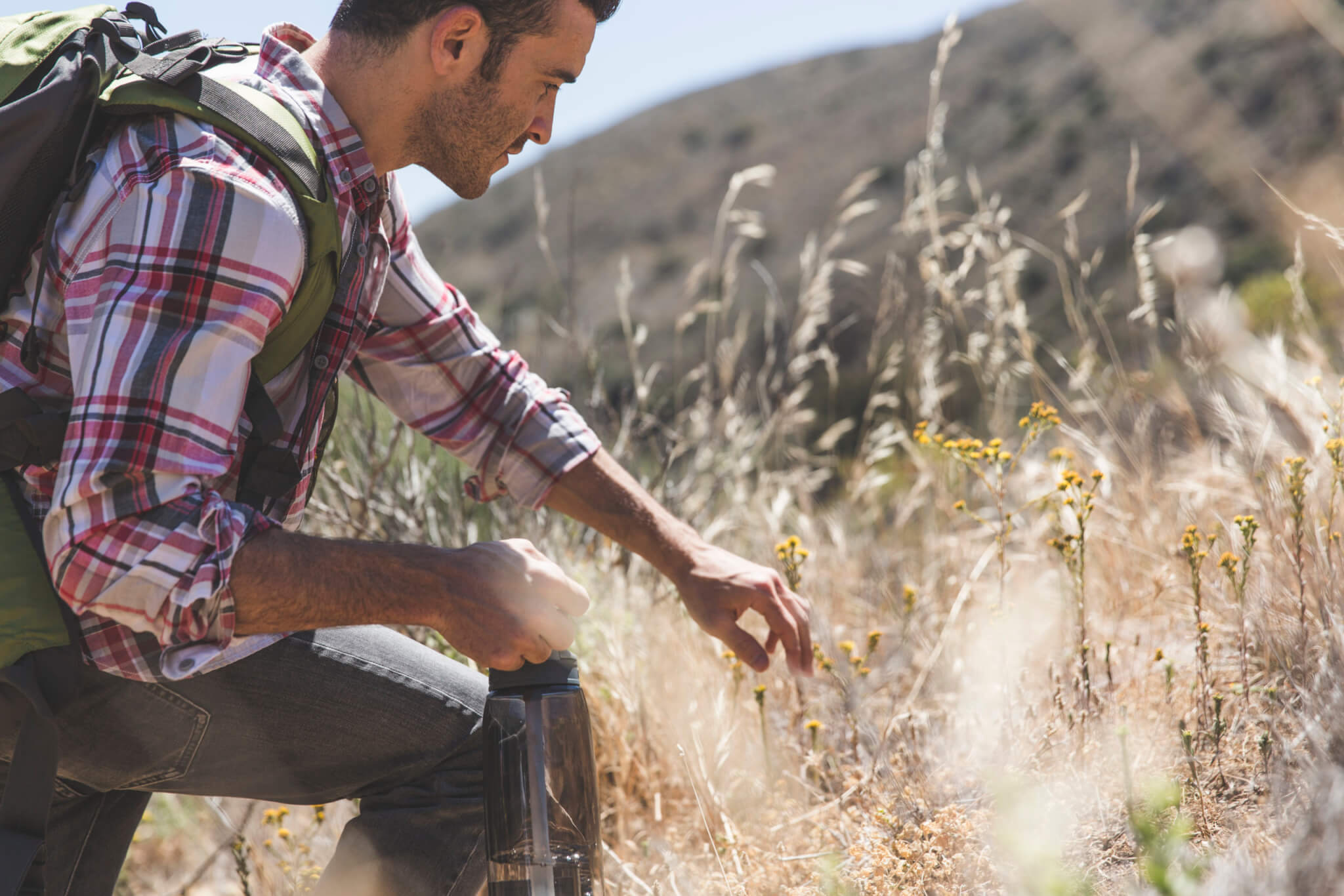 Side view of young man with backpack and water bottle hiking Elevate men's health