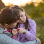 Sad daughter rests on mothers shoulder outside