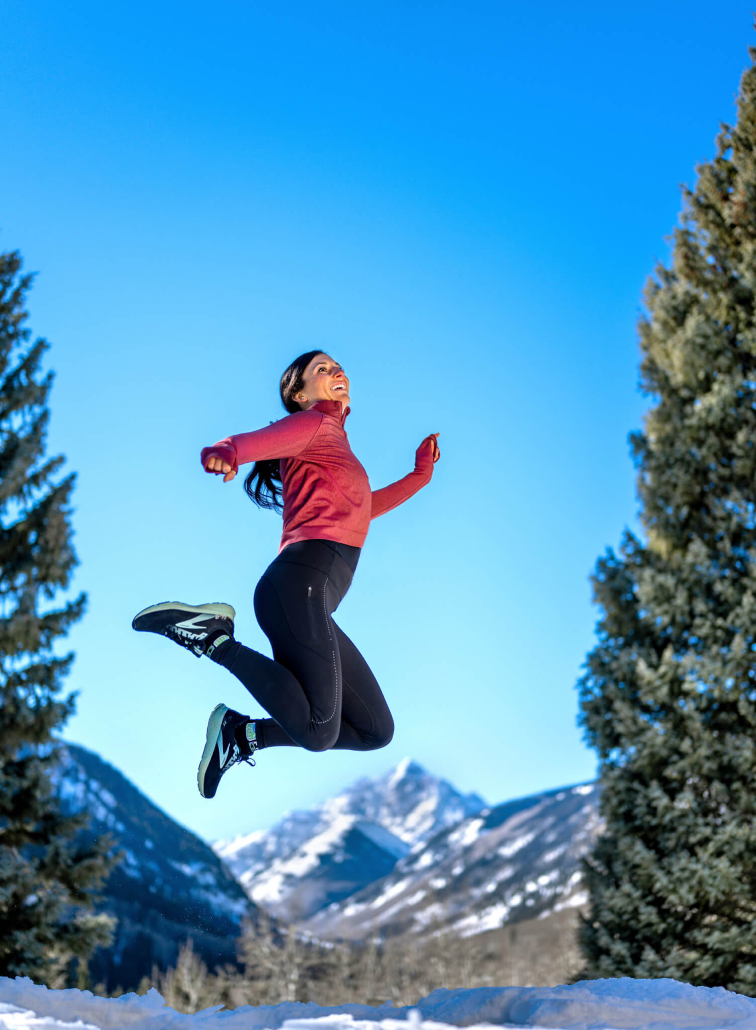 woman in workout clothes jumping in snowy woods