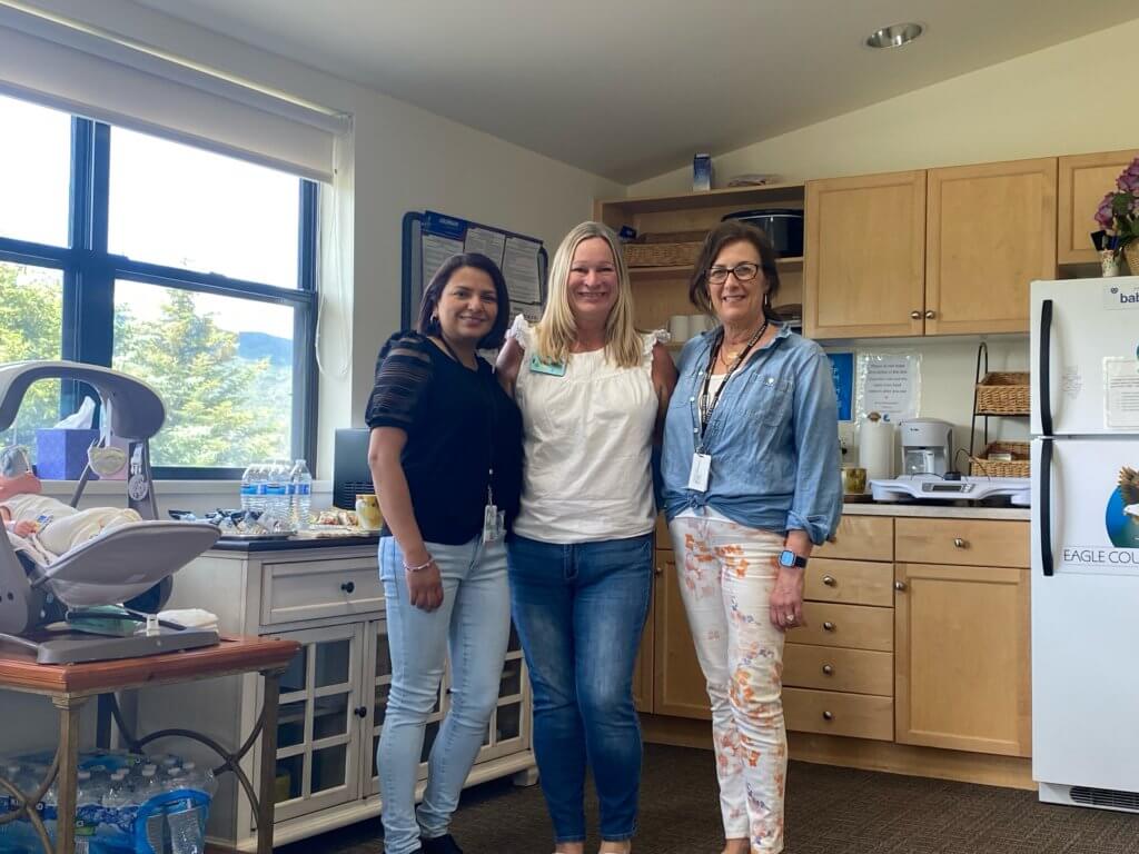three women smiling next to newborn