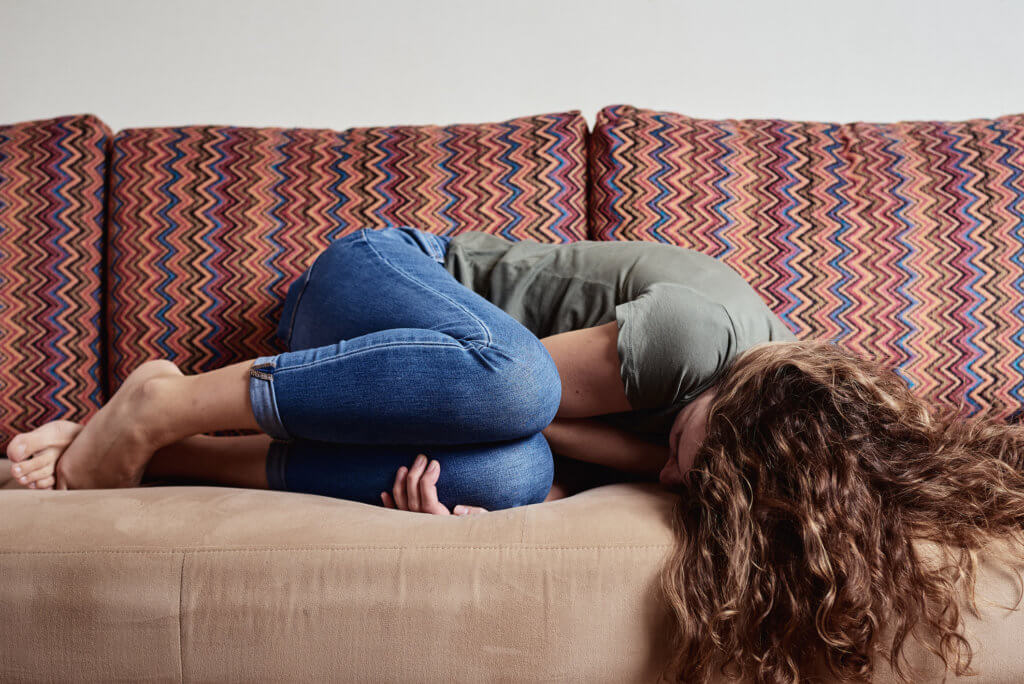 Woman Lying On Sofa, Suffering From Abdominal Pain what is endometriosis