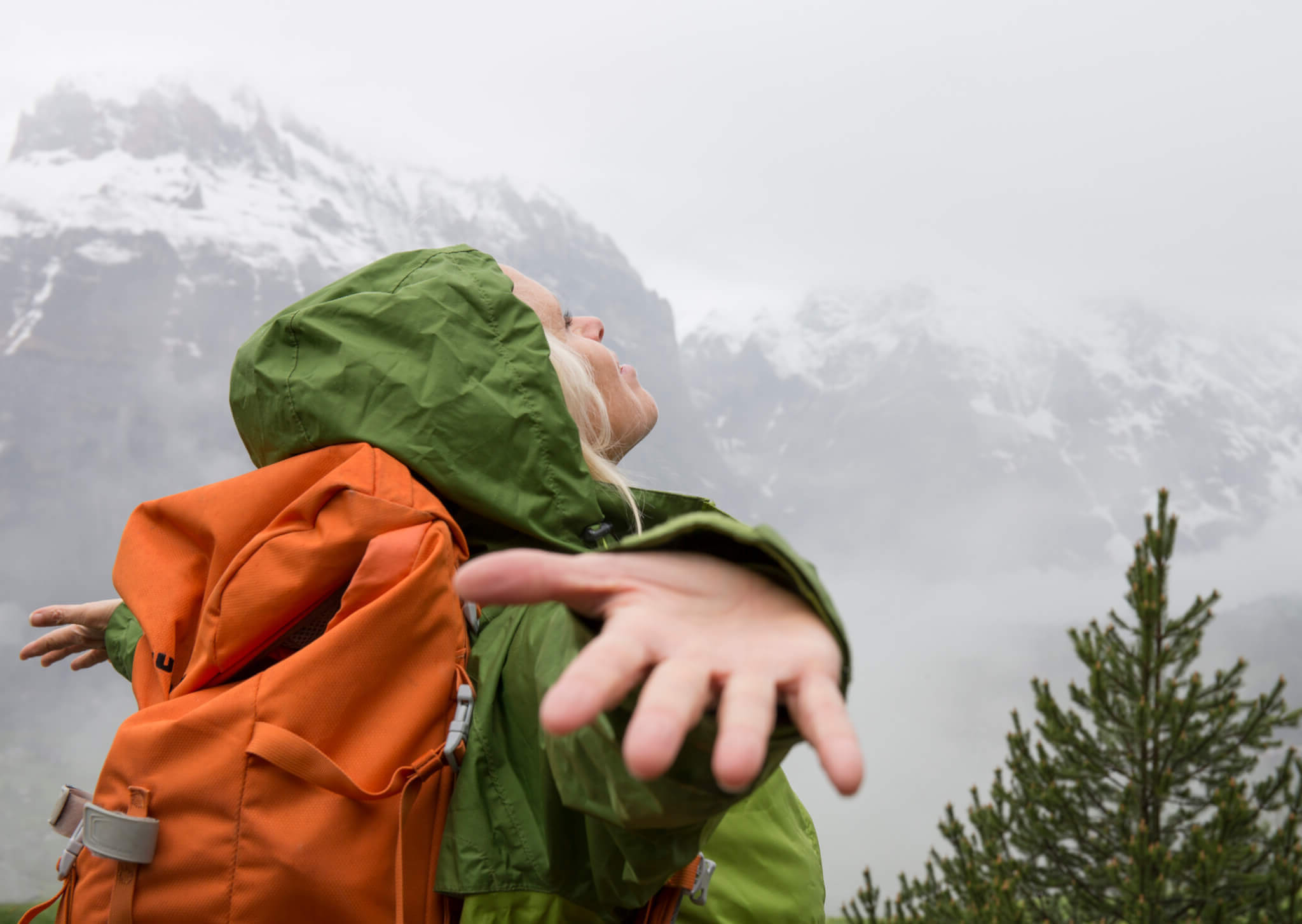 young woman hiker splaying arms out on top of mountain