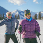 Two men laughing on skis in the mountains