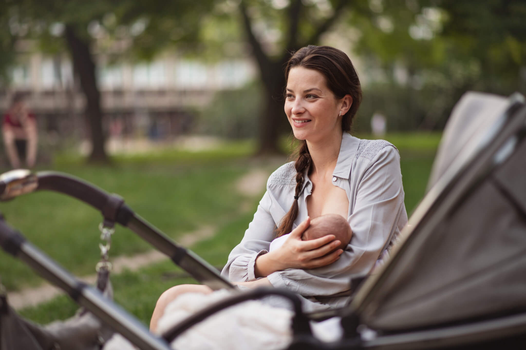 Young mother breastfeeding her baby outside in park