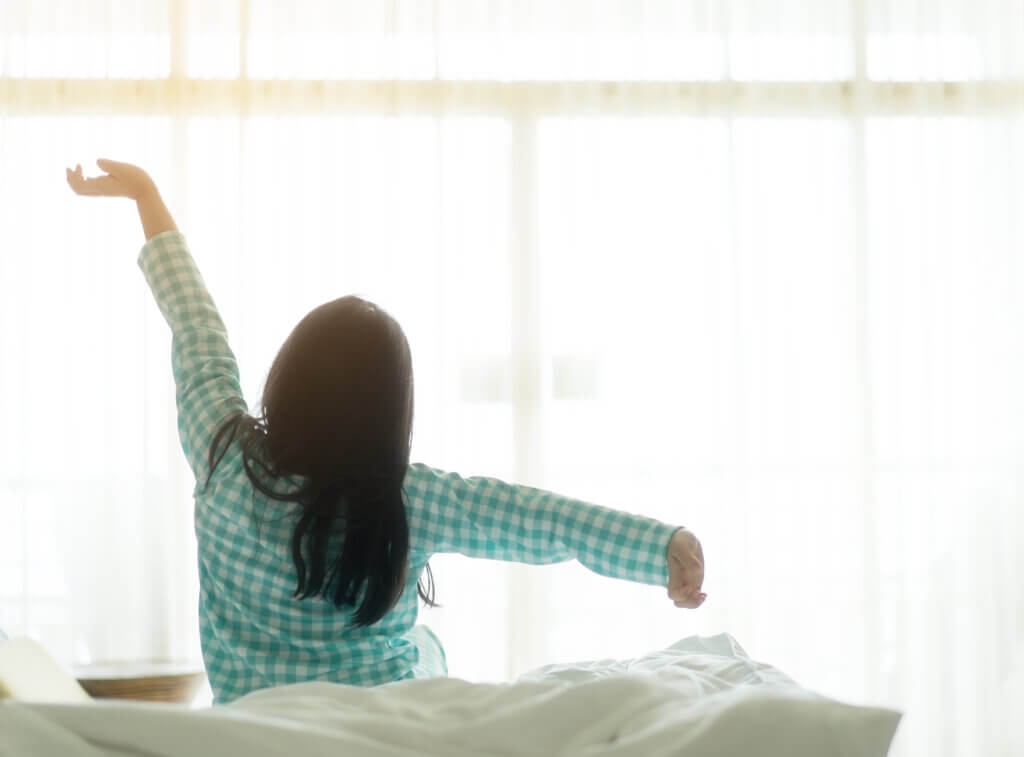 back of dark-haired child waking up stretching after sleep - creating a back-to-school routine