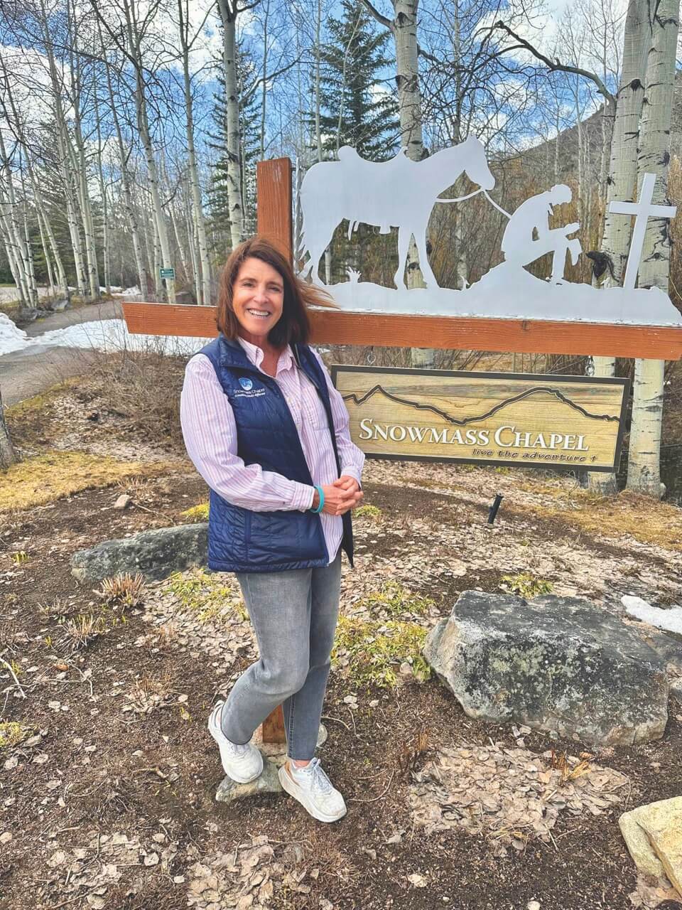 Marion Garrett smiling in front of Snowmass Chapel sign