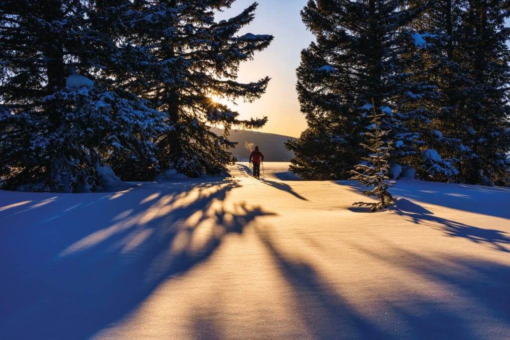 Outdoor Adventure Ski Touring with Scenic Mountain Backdrop - Man recreating on alpine touring skis while skiing high on mountain ridge with scenic views and warm sunset light.