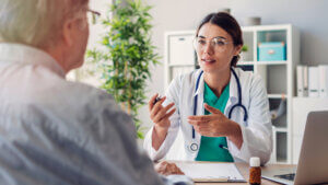 Female doctor and senior male patient discussing at clinic