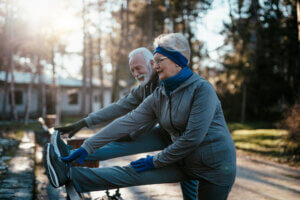 An older married couple enjoys exercising and jogging on a beautiful sunny winter day.