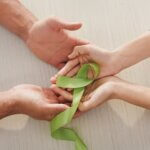 Hands with green ribbon for kidney awareness month