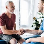 selective focus of happy patient shaking hands with doctor
