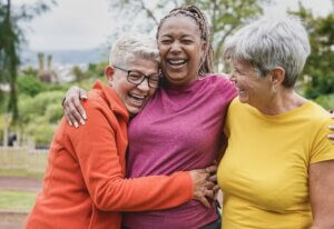 Happy multiracial senior women having fun together at park - Elderly generation people hugging each other outdoor environment positive impact on health