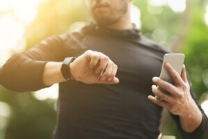 Closeup of unrecognizable man checking workout data on fitness tracker after intensive training outdoors how to train for backpacking
