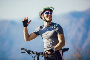 Portrait of mountain biker with helmet and sunglasses listening to music and smiling.