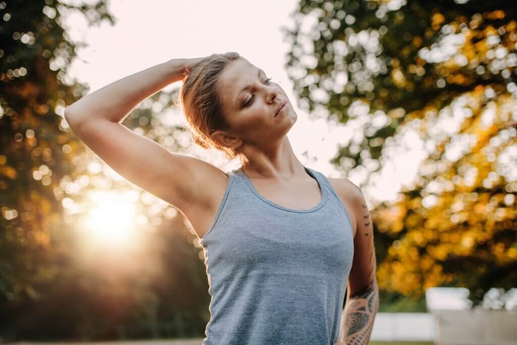 Portrait of healthy young woman stretching her neck outdoors. 