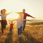 Happy family: mother, father, children son and daughter on nature on sunset health insurance season