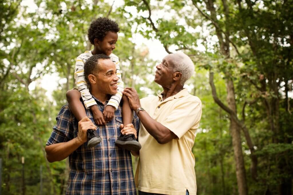 Boy (6-7) face to face with grandfather in forest