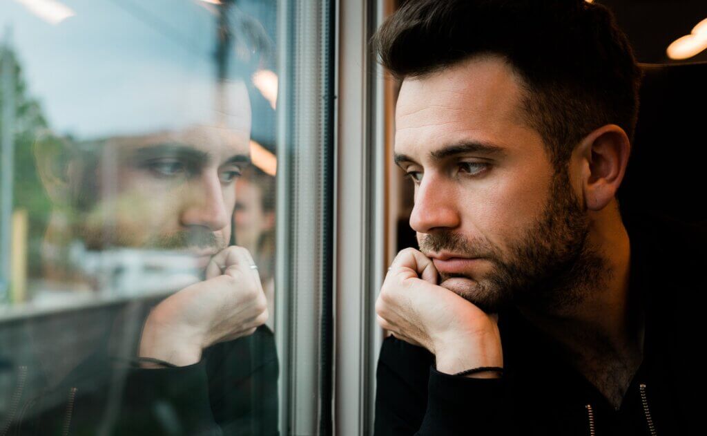 Young bearded man traveling by train in late afternoon