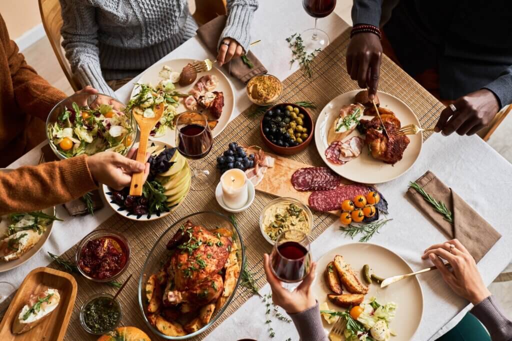 healthy meals holiday leftovers High angle view at diverse group of friends enjoying homemade food at festive dinner table with roasted turkey or chicken, copy space