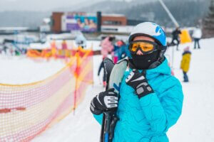 young adult woman in sport ski wear in helmet and eyeglasses. ski resort on background. winter activity